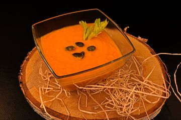 Hausgemachte Karotten-Ingwer-Suppe mit Kürbiskernen in Glasschale