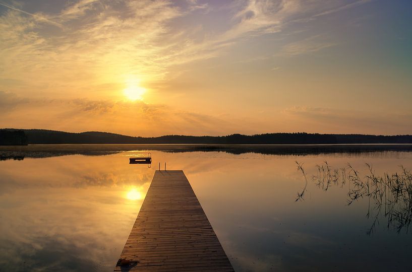 Footbridge, to the sunrise, reaching into a Swedish lake by Martin Köbsch