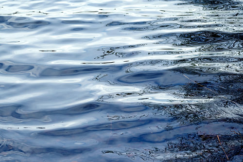 Blaue Wasseroberfläche mit glatten Wellen und Reflexion als Hintergrundtextur, Kopierraum