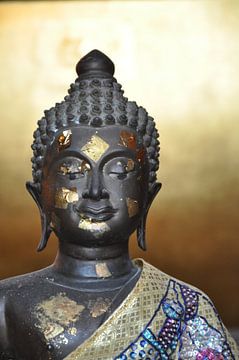 A serene Buddha statue with gold accents and colourful robes against a warm background. by UMA Digital NL