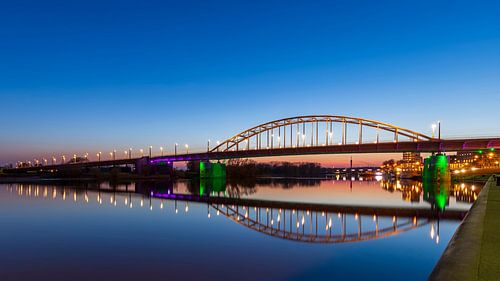 De Arnhemse John Frostbrug 's avonds boven een vlakke Rijn