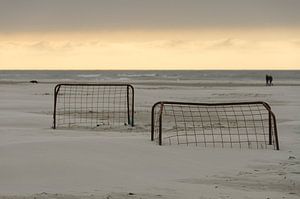 Voetbalgoals op een strand bij zonsondergang