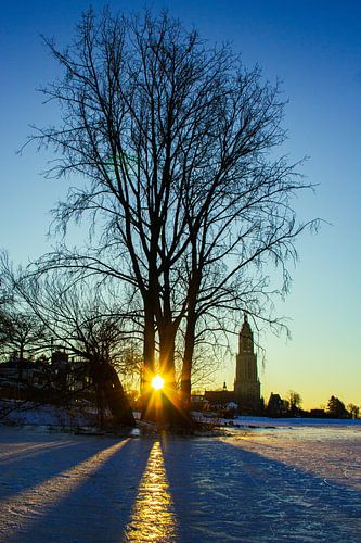 Lever de soleil sur un lac gelé avec une petite église. sur Sara de Leede