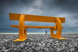 Orange bench on the pebble beach of Le Tréport, French Normandy with twosome on the horizon