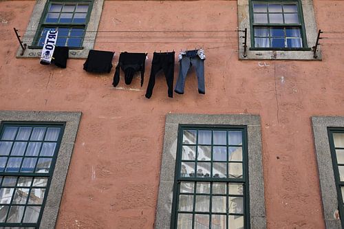 Wäscheleine mit Wäsche zwischen Fenstern in Porto