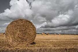 Strorollen op een akker met mooie wolkenluchten van Ans Bastiaanssen