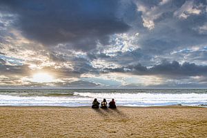 Drei Frauen am Strand bei Bewölkung und Sonnenuntergang