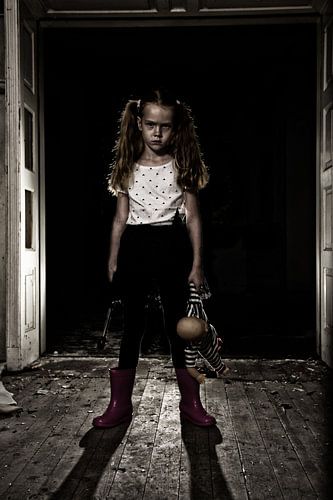 Unheimliches Mädchen mit Puppe und Hammer in verlassenem Haus