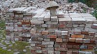 gestapelte Ziegel und alter Bauhelm auf einer Baustelle von Babetts Bildergalerie Miniaturansicht