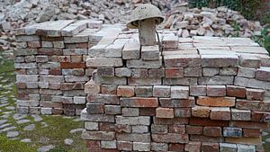 gestapelte Ziegel und alter Bauhelm auf einer Baustelle
