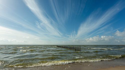 Marker wadden golfbrekers en uitwaaierende wolken