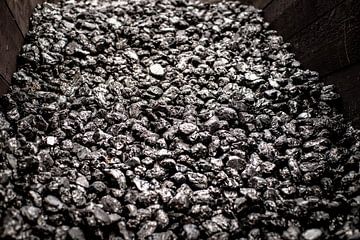 Opgestapelde zwart glimmende kolen in een houten box voor oude industrie