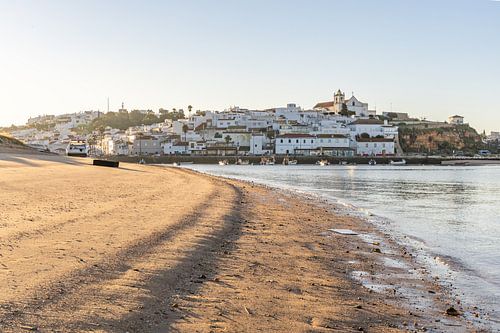 Zandstrand in de ochtend met uitzicht op het historische centrum van Ferragudo, Portimão, Algarve, Portugal