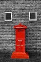 Red letterbox against wall in black and white