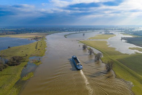 Vrachtschip dat op de IJssel vaart bij hoogwater