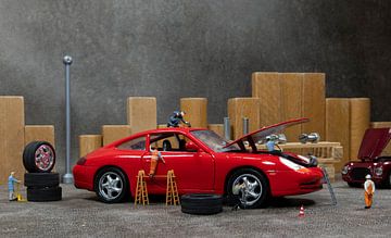 les miniatures du little world travaillent dans un garage pour réparer une voiture, changer les pneu