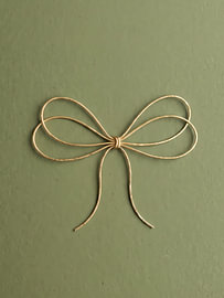 Elegante goldene Schleife auf salbeigrünem Hintergrund – Minimalistische Weihnachtswanddekoration von haroulita