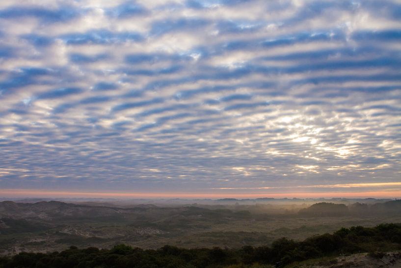cloud cover with breaking sun over dunes with fog by Menno van Duijn