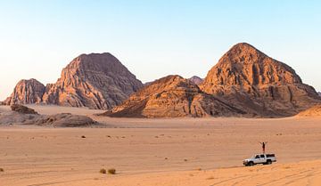 Een man staand op een jeep in de Wadi Rum woestijn in Jordanië van Claudio Duarte
