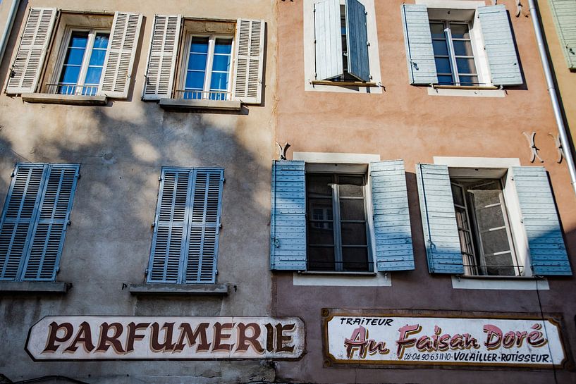 Enseigne de parfumerie à côté de l'enseigne de traiteur sur une façade provençale par Frans Scherpenisse