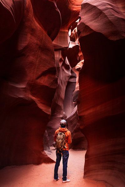 L'homme se tient parmi les dessins rupestres ondulants dans le Lower Antelope Canyon par Moniek Kuipers