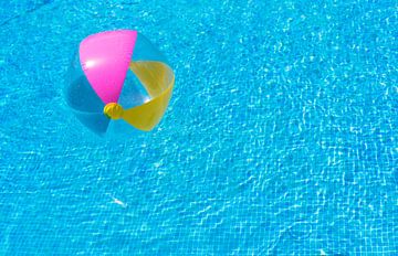 Opblaasbare kleurrijke strandbal vlotter op gegolfd blauw zwembad van Alex Winter