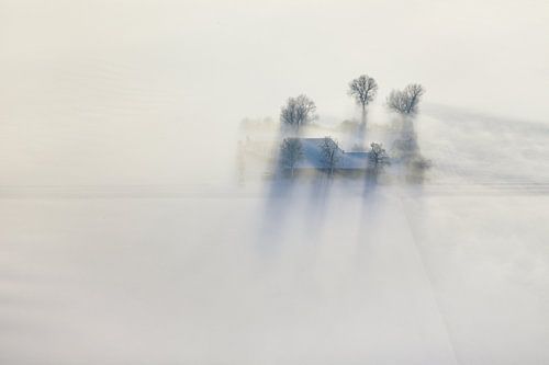 Luchtfoto van een winterlandschap, een boerderij in een zeldzame combinatie van sneeuw, zon en mist