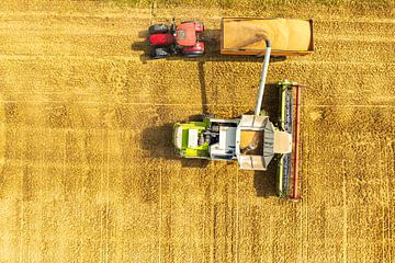Combine laadt de oogst in een transportwagen getrokken door een tractor van Sjoerd van der Wal Fotografie