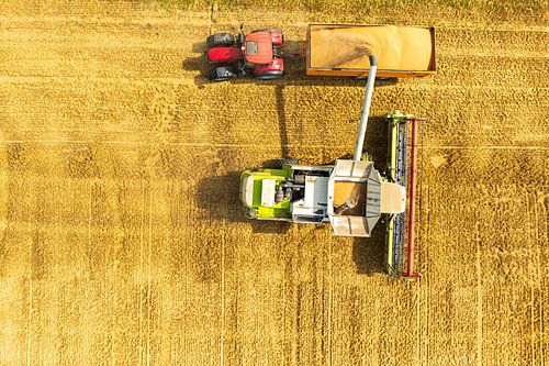 Moissonneuse-batteuse chargeant la récolte dans une remorque tirée par un tracteur