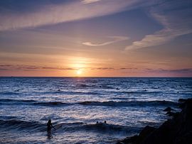 Surfers in the sea during sunset. by Sjoerd van der Hucht