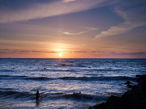 Surfeurs dans la mer au coucher du soleil.