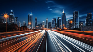 Autolichter, Lichtspuren auf der Autobahn bei Nacht mit Skyline im Hintergrund