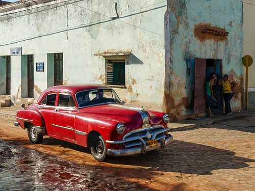Klassieke rode auto cruist door Cubaanse straten