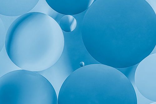 Des gouttes d'huile rondes sur l'eau, dans des tons bleus