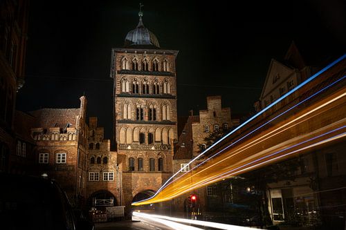 Lichtsporen van een bus die 's nachts door de poorttoren Burgtor van Lübeck rijdt, historisch bakste