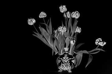 Nature morte en noir et blanc de tulipes rouges fanées dans un vase à tulipes bleu Delft. sur WorldWidePhotoWeb