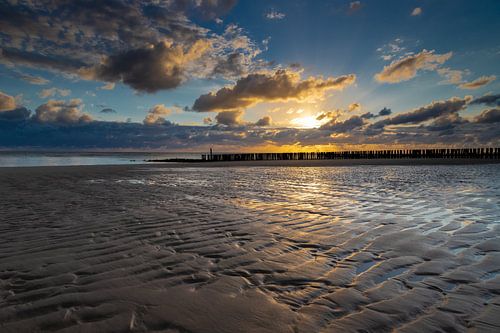 spectaculaire zonsondergang op het Zeeuwse strand met de typische Nederlandse golfbrekers