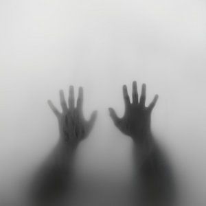 Les mains derrière la vitre dans le brouillard
