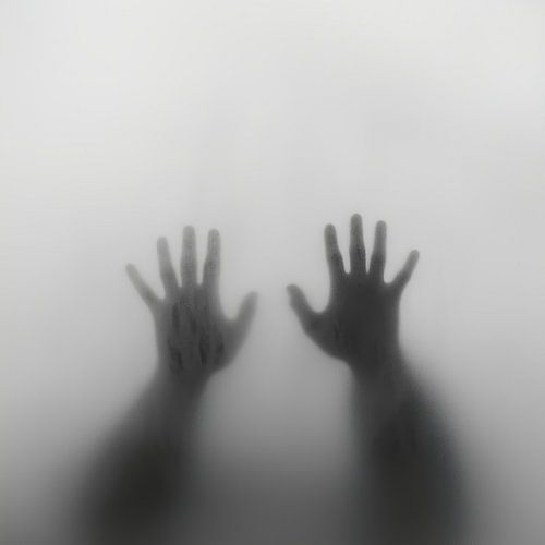 Hands behind the glass in the fog