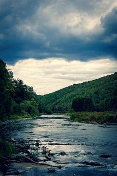 Een rivier op een donker bewolkte dag in de Belgische Ardennen omgeven door bergen en bos. van Joeri Mostmans