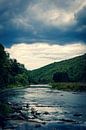 A river on a dark cloudy day in the Belgian Ardennes surrounded by mountains and forest. by Joeri Mostmans thumbnail