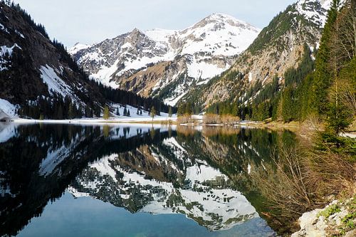De Vilsalpsee in het Tannheimer Tal met spiegelend water en een alpenberglandschap op de achtergrond.