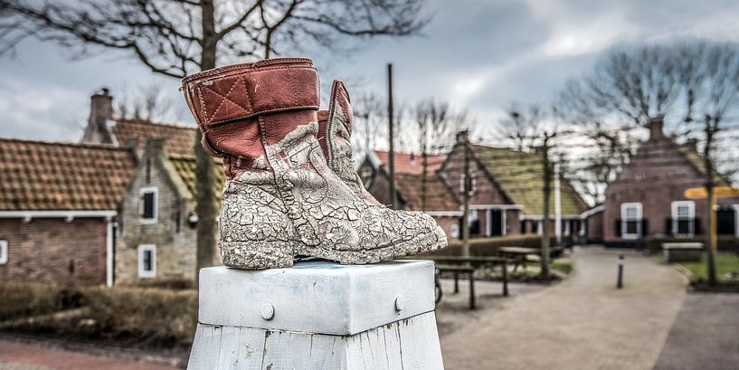 Boots on a bollard in the village of PaesensModdergat in Friesland. by Harrie Muis
