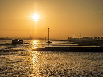 Binnenvaartschip glijdt door de mist bij zonsopgang langs de Waal