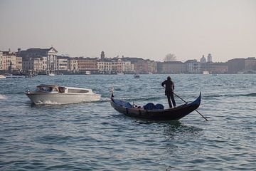 Man op gondola voor de oude stad Venetie in Italie