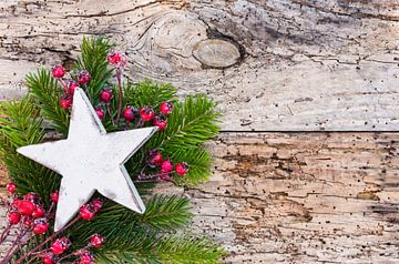 Weißer hölzerner Weihnachtsstern mit Tannenzweig und roten Beeren auf rustikalem Holzhintergrund von Alex Winter