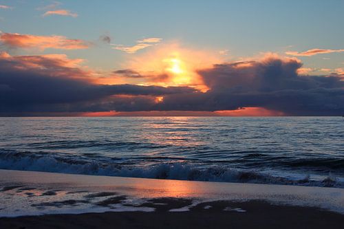 Setting sun with clouds on the Maasvlakte beach'.