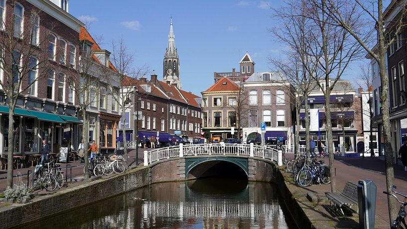 Gracht in Delft met uitzicht op een brug en grachtenpanden van Gert Bunt