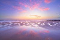 A sky full of evening red reflects on the wet sand of the st