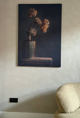 Stillleben mit goldener Vase vor dunklem Hintergrund